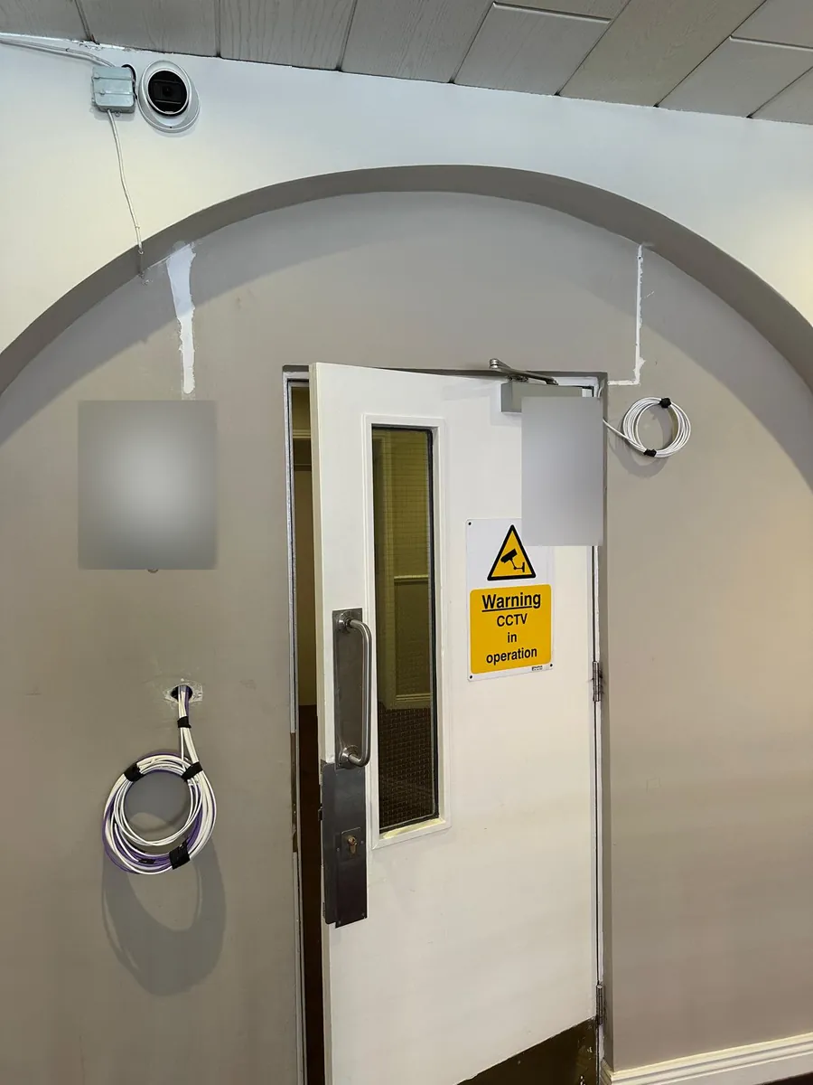 Cable left ready beside a common-area door, with CCTV overhead